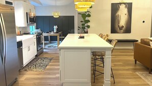 Une cuisine moderne avec des meubles blancs, un îlot central et des luminaires suspendus.