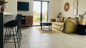 A modern living room with a sofa, chairs, a coffee table, and a TV mounted on the wall. - 🌴 Villa Capeline Sea View Haven - Pool & tropical garden 2 min. from the lagoon (Saint-Paul)