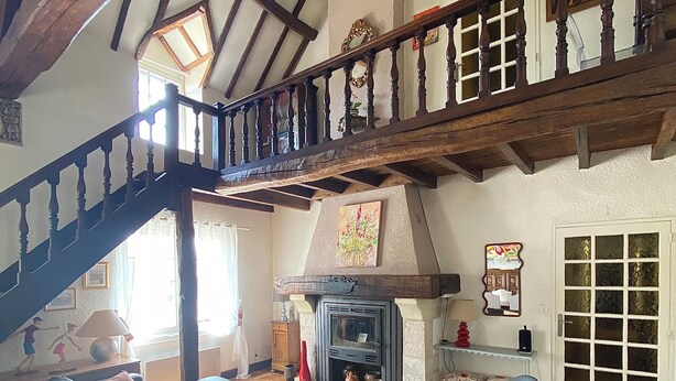 A spacious living room with a fireplace, a black leather sofa, a wooden staircase, and a tiled floor. - Large charming house with swimming pool, huge garden and close to state forest (Saint-Laurent)