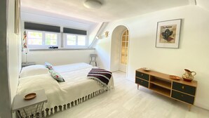 A bedroom with a bed, a small table, a dresser, a window, and a door. - Large charming house with swimming pool, huge garden and close to state forest (Saint-Laurent)