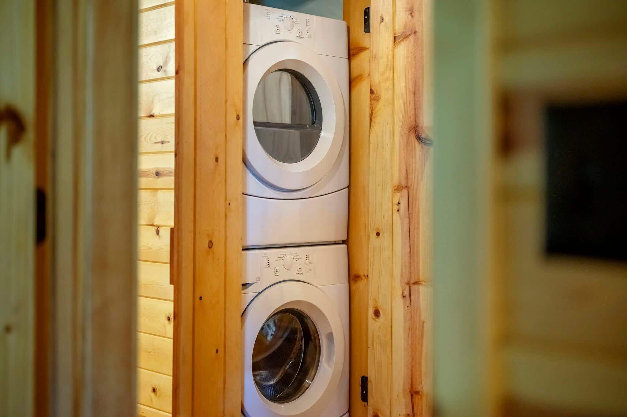 A laundry room with two stacked washing machines in a wooden enclosure.
