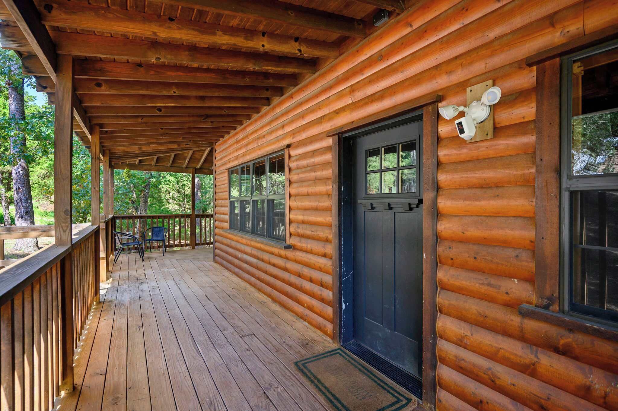 A wooden cabin with a covered porch, large windows, and a black door.
