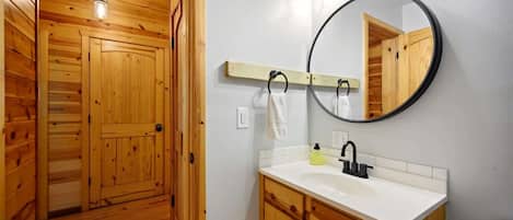 Un baño con paneles de madera, un lavamanos blanco, un espejo y un inodoro.