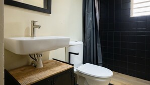 A bathroom with a white sink, toilet, and a shower curtain. - Aki Banda Suites (Willemstad)