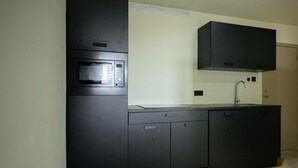 A kitchen with a built-in microwave, a sink, and black cabinets. - Aki Banda Suites (Willemstad)