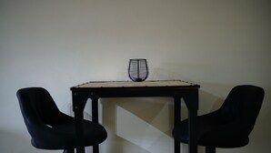 A small table with a wireframe object on top, flanked by two black chairs. - Aki Banda Suites (Willemstad)