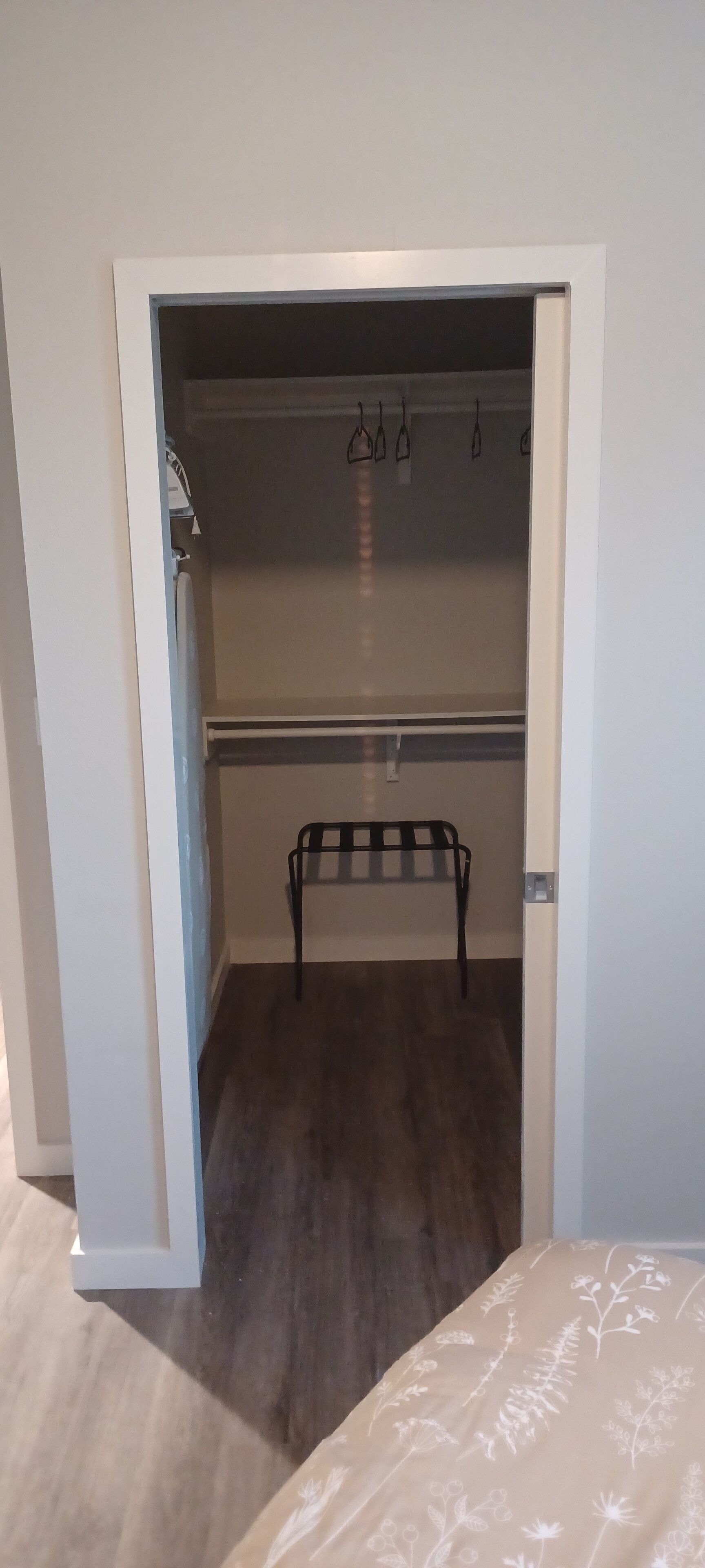 An open closet with a hanging rack and a bench.