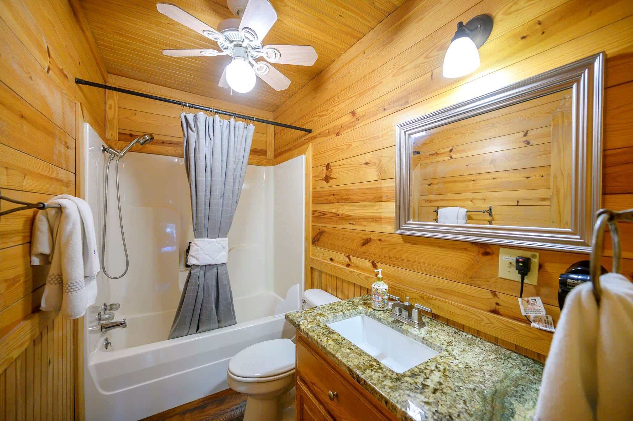 A wooden cabin bathroom with a shower, toilet, sink, and vanity.
