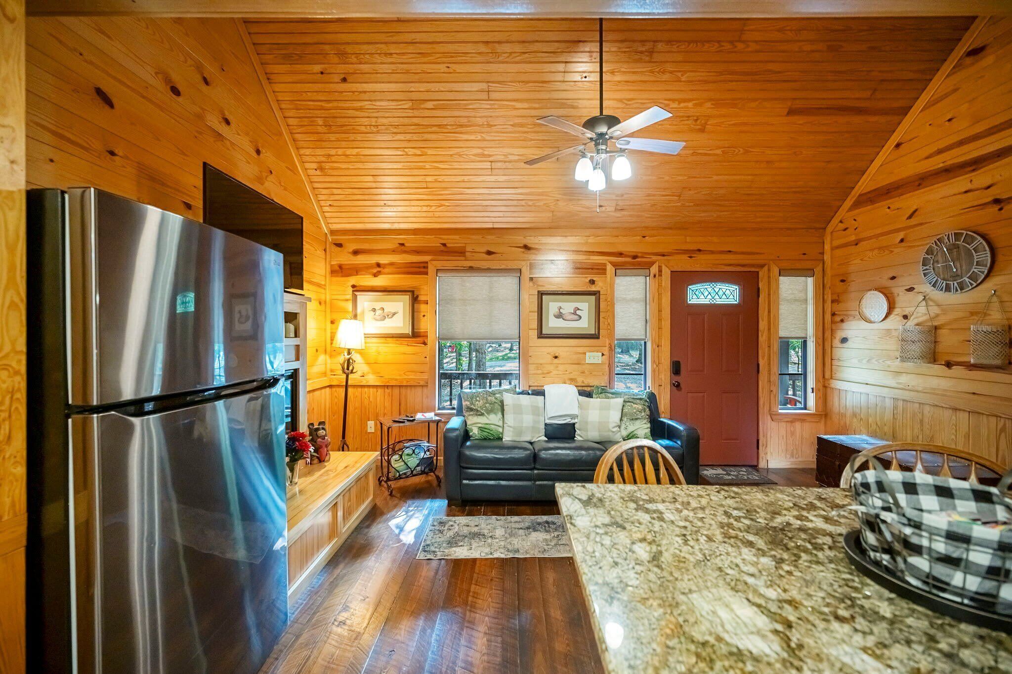 A wooden cabin interior with a kitchen, dining area, and living room.