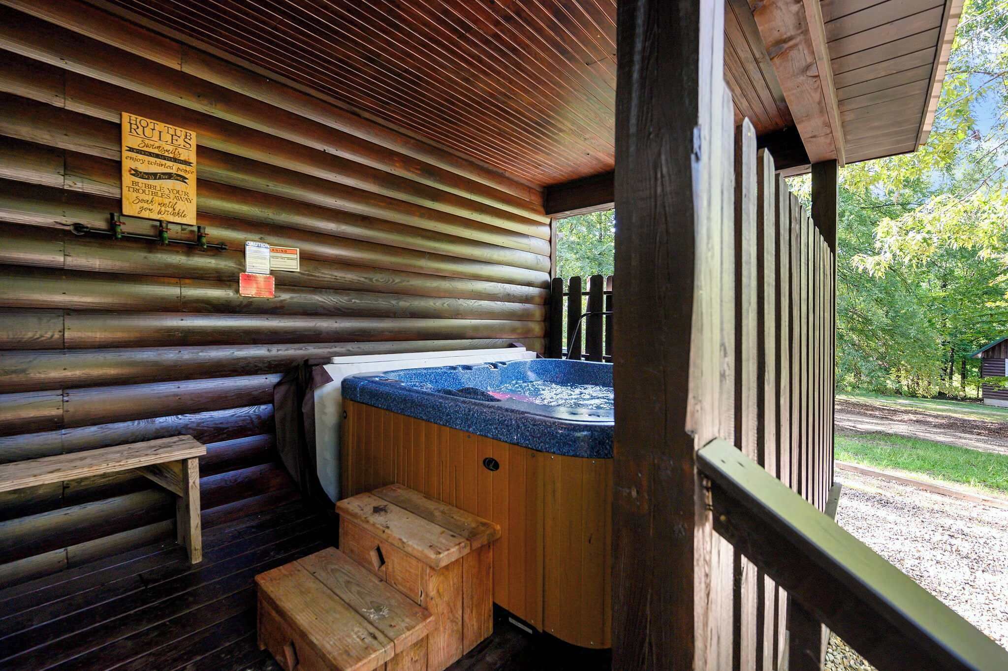 Eine Holzhütte mit Whirlpool, Holzbanken und einem Schild mit Regeln.