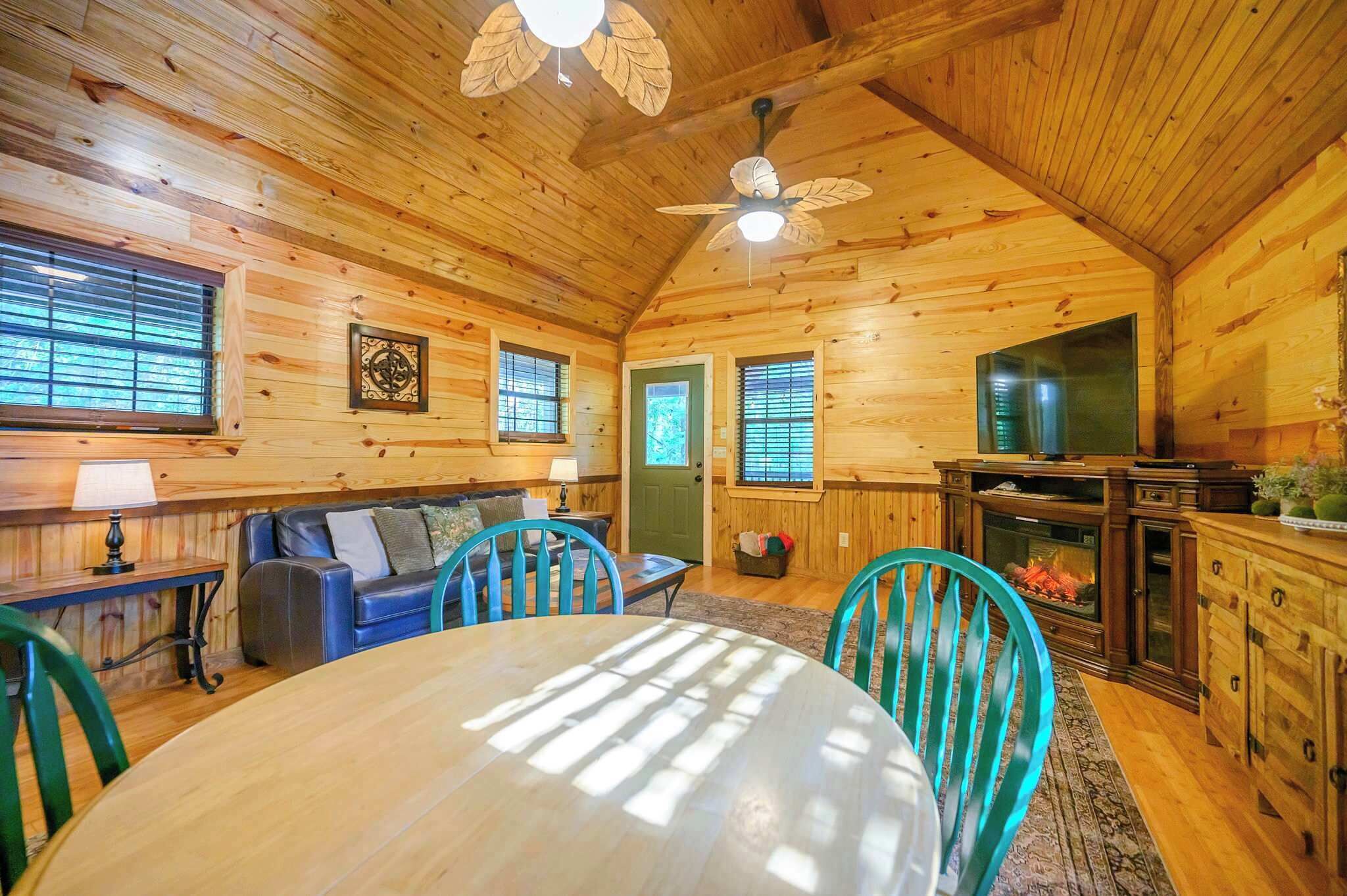 A cozy cabin interior with a wooden interior, a fireplace, a dining area, and a kitchen.