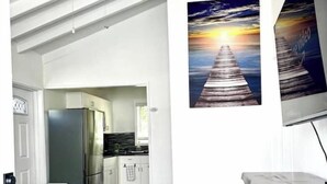 Une cuisine moderne avec des meubles blancs, un réfrigérateur en acier inoxydable et un plancher en bois.