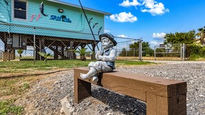 Una statua di un bambino seduto su una panchina di fronte a un edificio color turchese con un cartello che recita 'St. Jude's'.