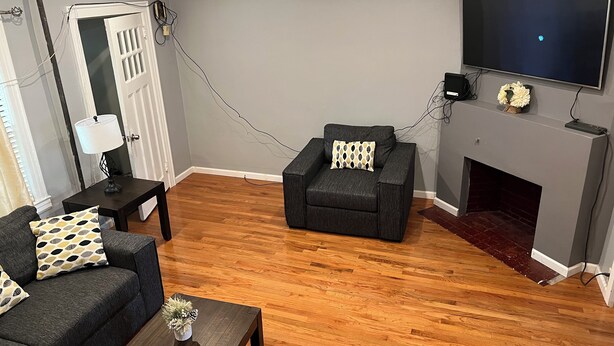A living room with a fireplace, a sofa, a coffee table, and a TV mounted on the wall. - Charming apartment in awesome Brooklyn. (Brooklyn)