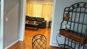 A dining area with a round table, a chair, a ceiling fan, and a view into a living room with a sofa and curtains. - Charming apartment in awesome Brooklyn. (Brooklyn)