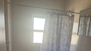 A bathroom with a bathtub, toilet, sink, and a window with a curtain. - Charming apartment in awesome Brooklyn. (Brooklyn)