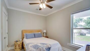 A bedroom with a bed, a ceiling fan, a window, and a view of the outside.