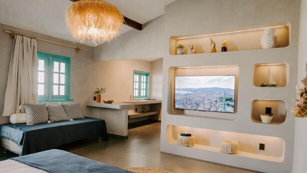 A modern bedroom with a large bed, a desk, a TV, and a view of a cityscape. - Pousada Boutique Preá Beira Mar - Raro Life (Cruz)