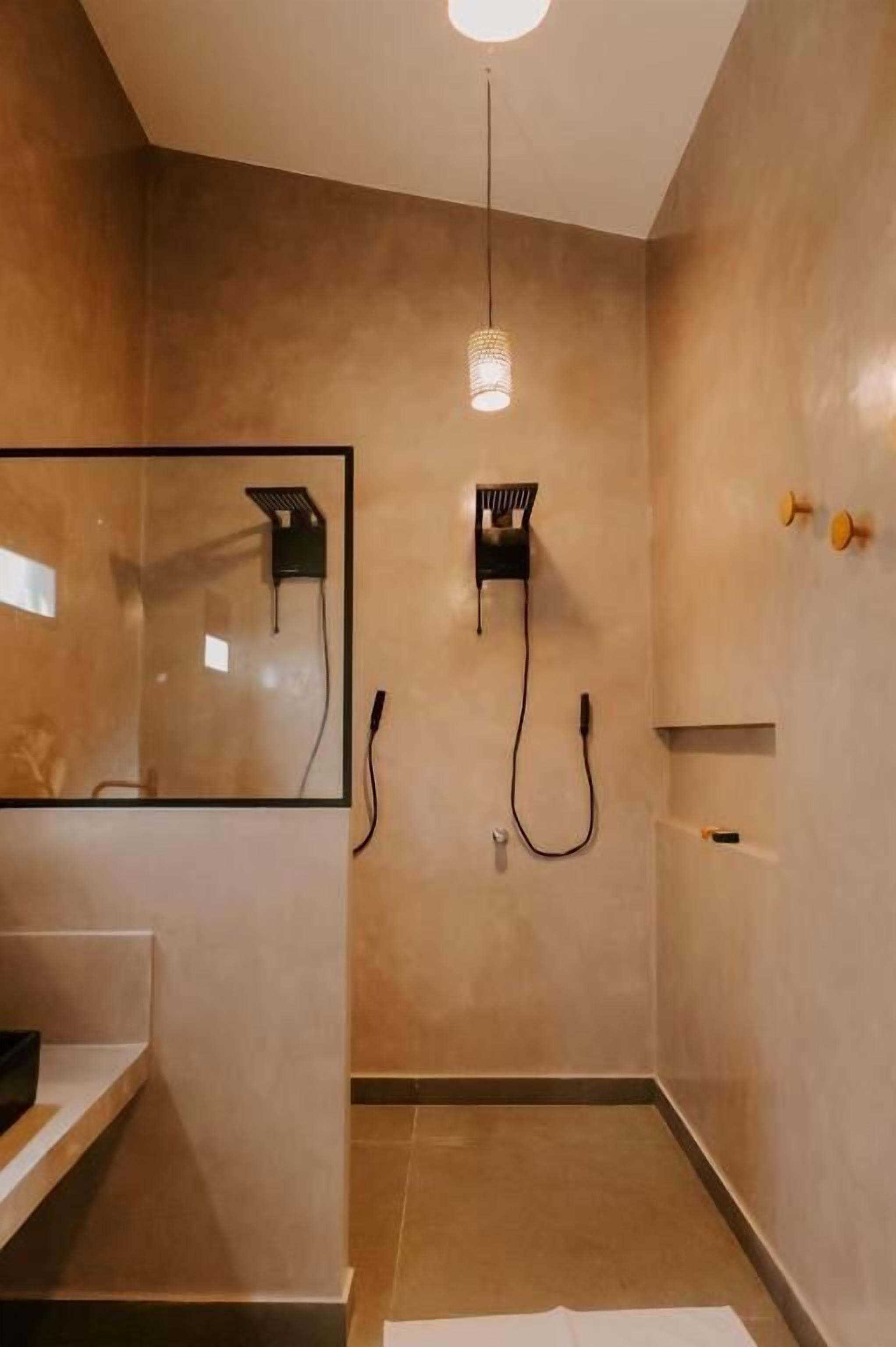 Une salle de bain moderne avec un grand miroir, une douche équipée d’un pommeau de douche à main et un porte-serviettes.
