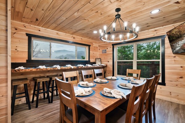 Comedor de madera con una mesa grande, sillas y una araña.