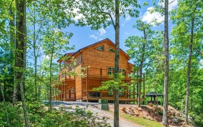 A multi-story log cabin with a balcony, surrounded by trees. - Luxury Smoky Mtn Cabin, Sleeps 12, Arcade, Hot Tub, Mountain Views, 2 Kitchens (Pigeon Forge)