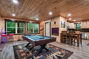 A pool table in a room with wooden walls and a window. - Spacious Mountain Cabin with Hot Tub, Sleeps 12 (Pigeon Forge)