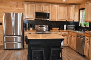 Una cocina moderna con armarios de madera, electrodomésticos de acero inoxidable y una encimera negra.