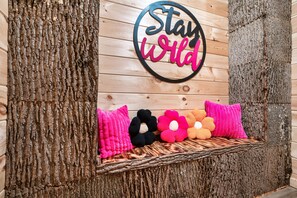 Una pared con un letrero que dice 'Stay Wild' y un estante con almohadas coloridas.