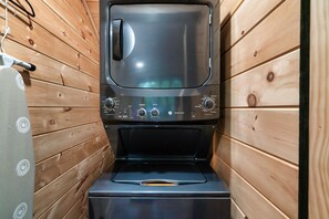 Una cocina compacta y moderna con paredes de madera, horno empotrado y microondas.