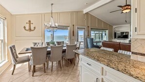 Cocina amplia con una isla grande, comedor con sillas y vistas al océano.