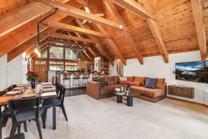 A spacious loft with a high ceiling, a dining area, a living room with a sofa, and a kitchen in the background. - 4BR Tahoe Cabin w/ Hot Tub, BBQ & Ping Pong Next to Lake & Paige Meadows Trails (Tahoe City)