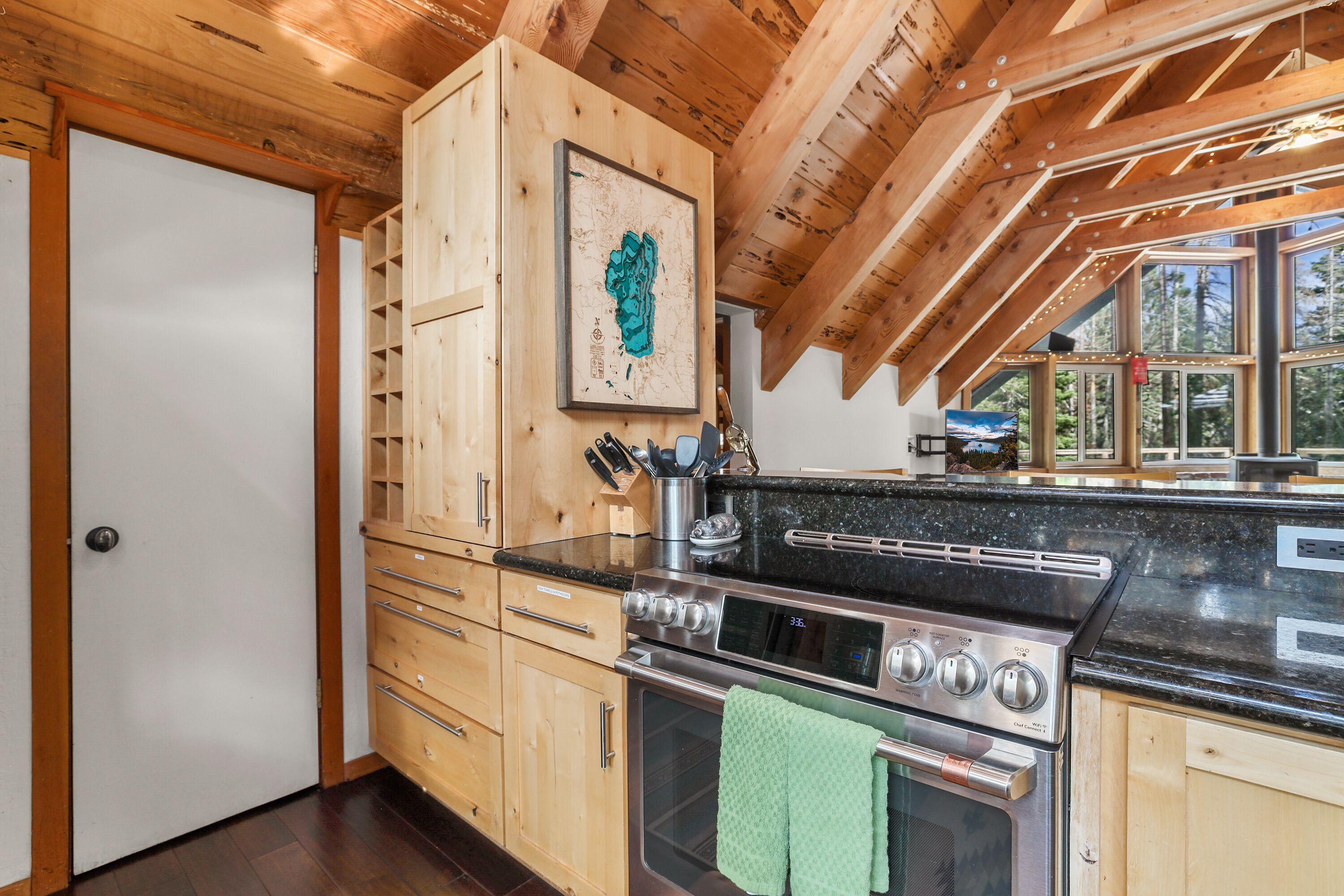 Une cuisine avec des meubles en bois, une cuisinière en acier inoxydable et une grande fenêtre.