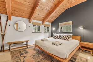 A bedroom with a wooden ceiling, a bed with white bedding, a round mirror, and a bench. - 4BR Tahoe Cabin w/ Hot Tub, BBQ & Ping Pong Next to Lake & Paige Meadows Trails (Tahoe City)