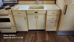 A compact kitchen with a sink, stove, and cabinets.