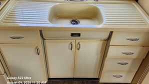 A vintage kitchen with a sink, cabinets, and a countertop.