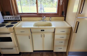 A compact kitchen with a sink, stove, and cabinets.