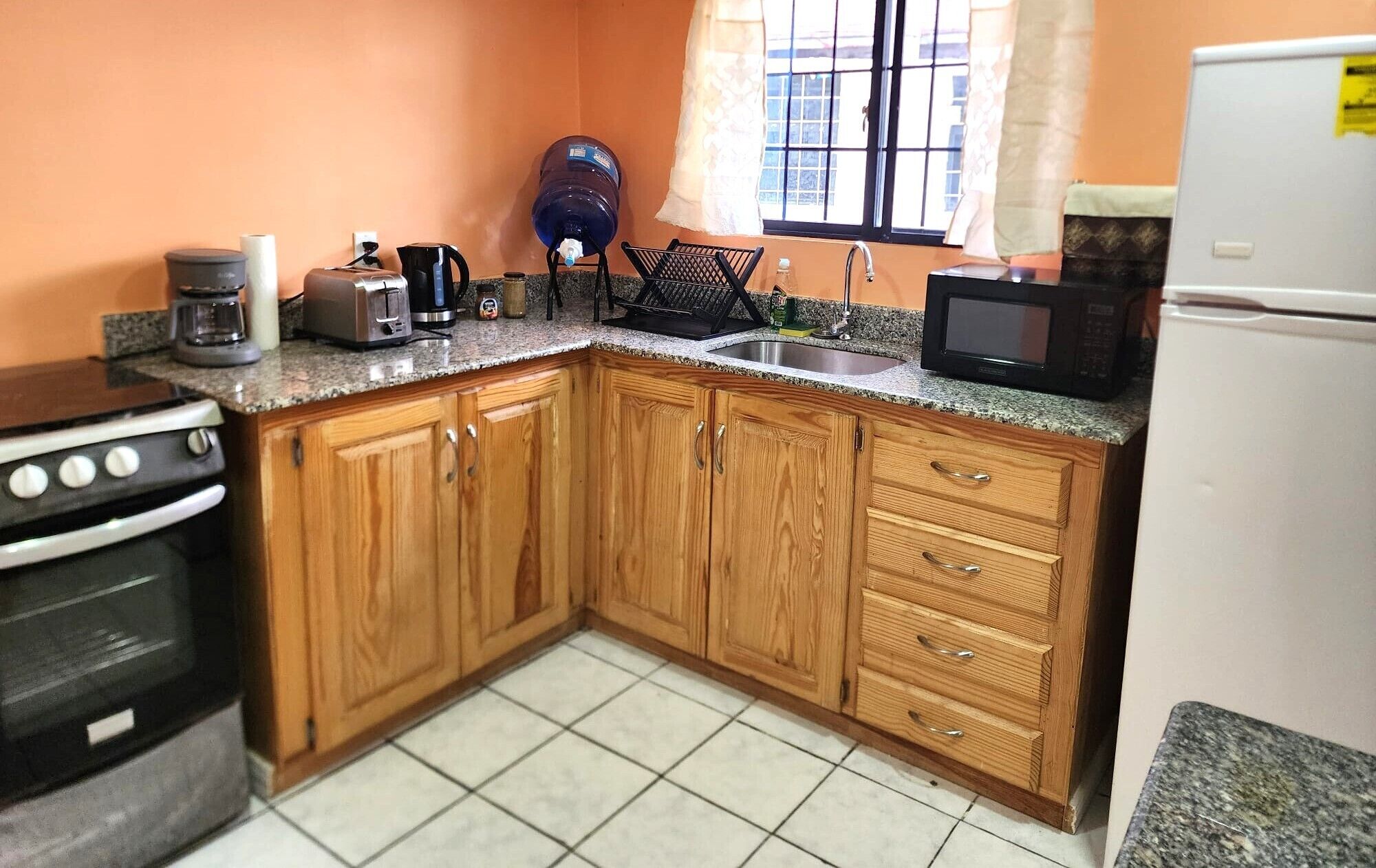 A kitchen with wooden cabinets, a stove, a microwave, a toaster, and a water dispenser.