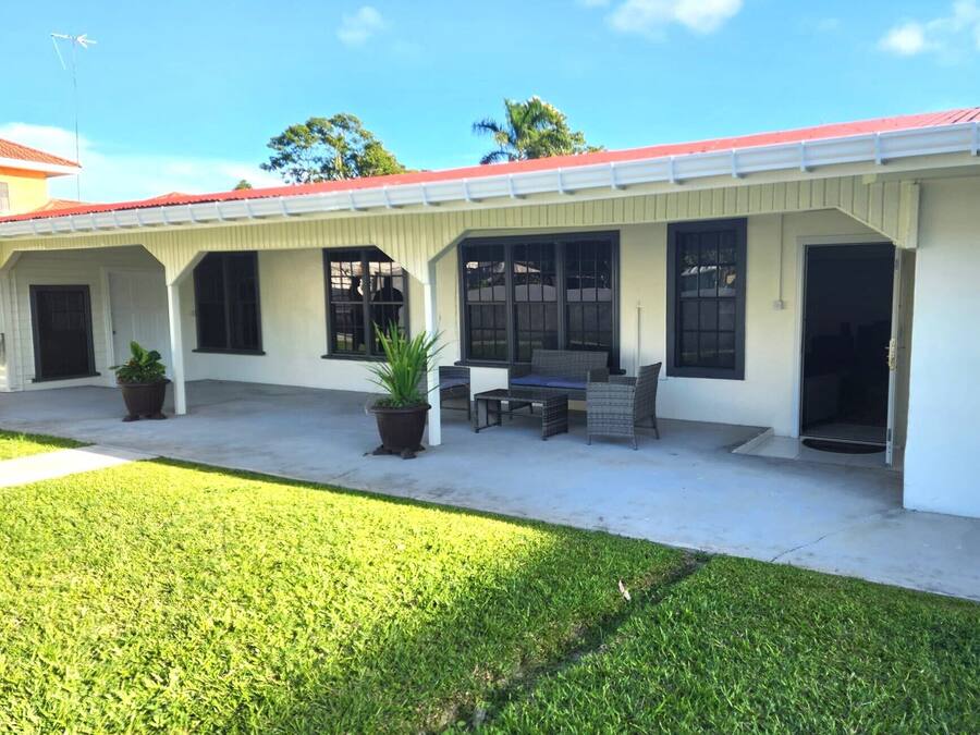 A two-story building with a covered patio area featuring outdoor seating and potted plants.