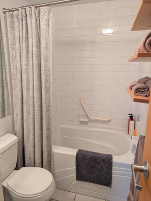 Une salle de bain équipée de toilettes, d’une baignoire et d’un rideau de douche.