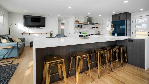 A modern kitchen with a white island, bar stools, and a TV mounted above the island. - Sleeps 16 - 15 min/Downtown, 10 min/Medical Center (Aurora)