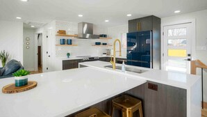 A modern kitchen with a central island, stainless steel appliances, and a hexagonal backsplash. - Sleeps 16 - 15 min/Downtown, 10 min/Medical Center (Aurora)