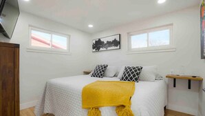 A bedroom with a bed, a yellow throw blanket, two windows, a painting, and a wooden nightstand. - Sleeps 16 - 15 min/Downtown, 10 min/Medical Center (Aurora)