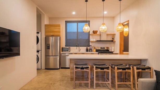 A modern kitchen with stainless steel appliances, a large island with bar stools, and pendant lighting. - Casita Backdoor: Jungle Retreat, Sleeps 4-6 (Nosara)