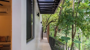 A narrow corridor with a balcony, a sofa, and a potted plant. - Casita Backdoor: Jungle Retreat, Sleeps 4-6 (Nosara)