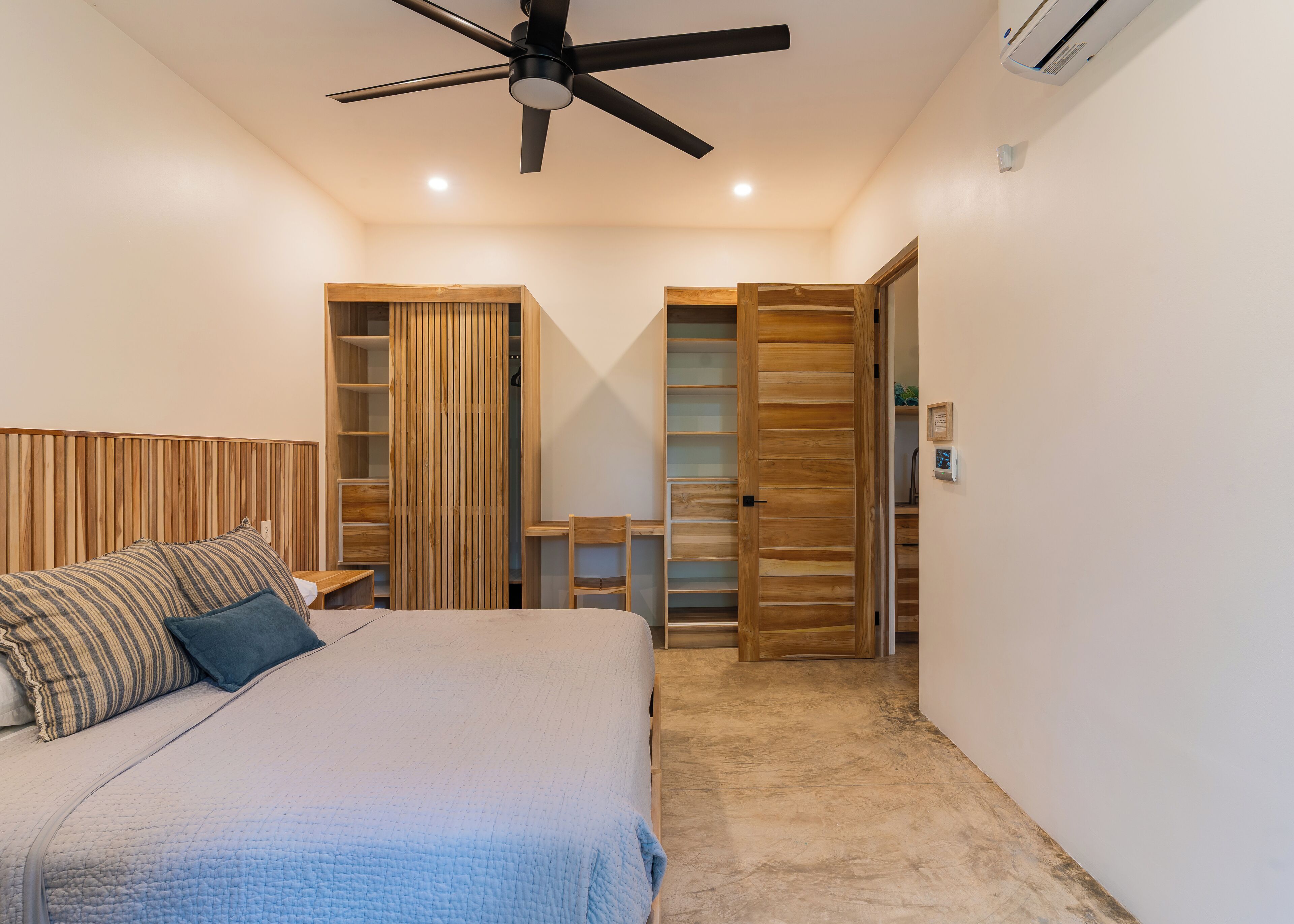 Een slaapkamer met een bed, een plafondventilator, een kledingkast en een bureau.