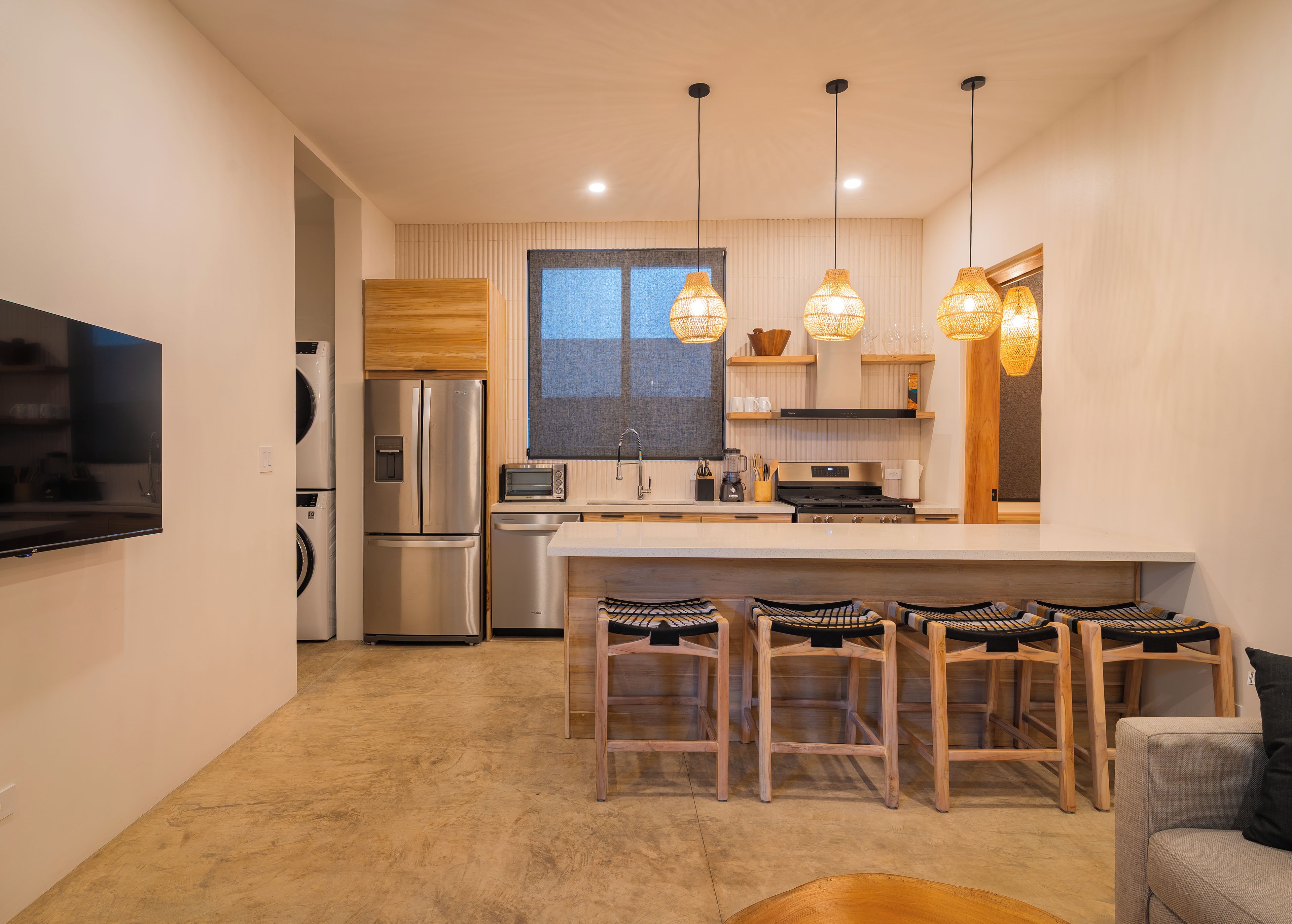 Una cocina moderna con electrodomésticos de acero inoxidable, una isla grande con taburetes de bar e iluminación colgante.