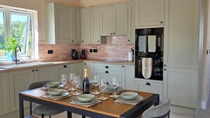 Una cocina moderna con armarios de tonos claros, un backsplash de ladrillo y un comedor preparado para seis comensales.