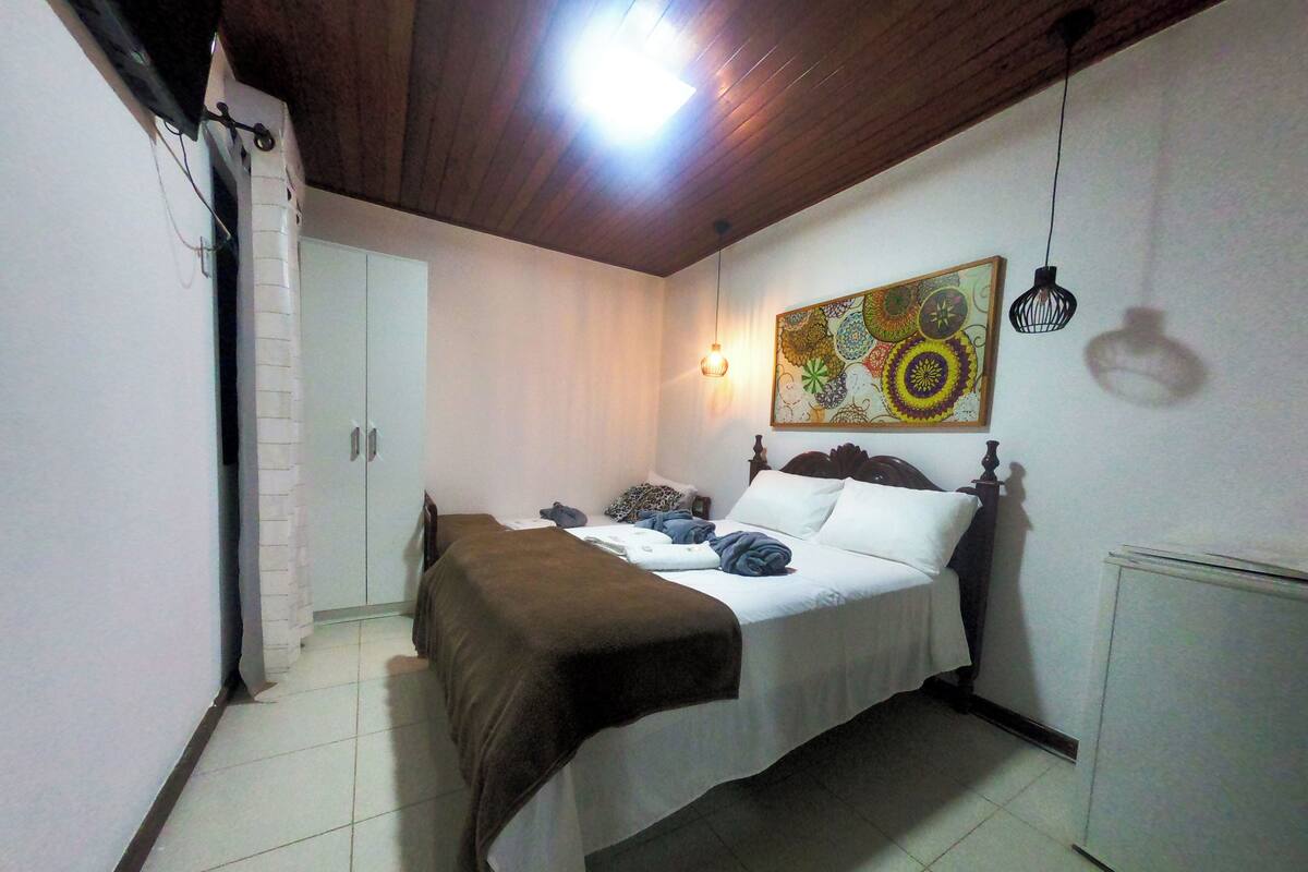 A bedroom with a bed, a wardrobe, a radiator, and a painting on the wall.