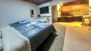 A bedroom with a bed, a bedside table, a mirror, and a sliding glass door leading to a kitchen area. - Pousada Liberte-se in Búzios  (Buzios)