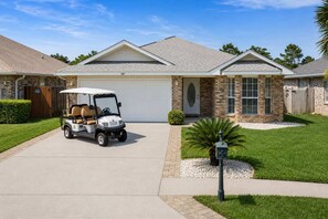 Ein Wohnhaus mit Garage, Auffahrt und Golfmobil auf der Auffahrt.